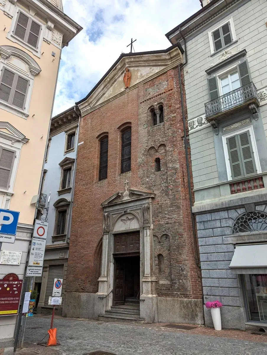 Chiesa Sant'Ulderico an der Piazza di Città besteht aus roten Backsteinen. Wie ein Reihenhaus ist sie zwischen 2 bunten Häusern eingeklemmt.