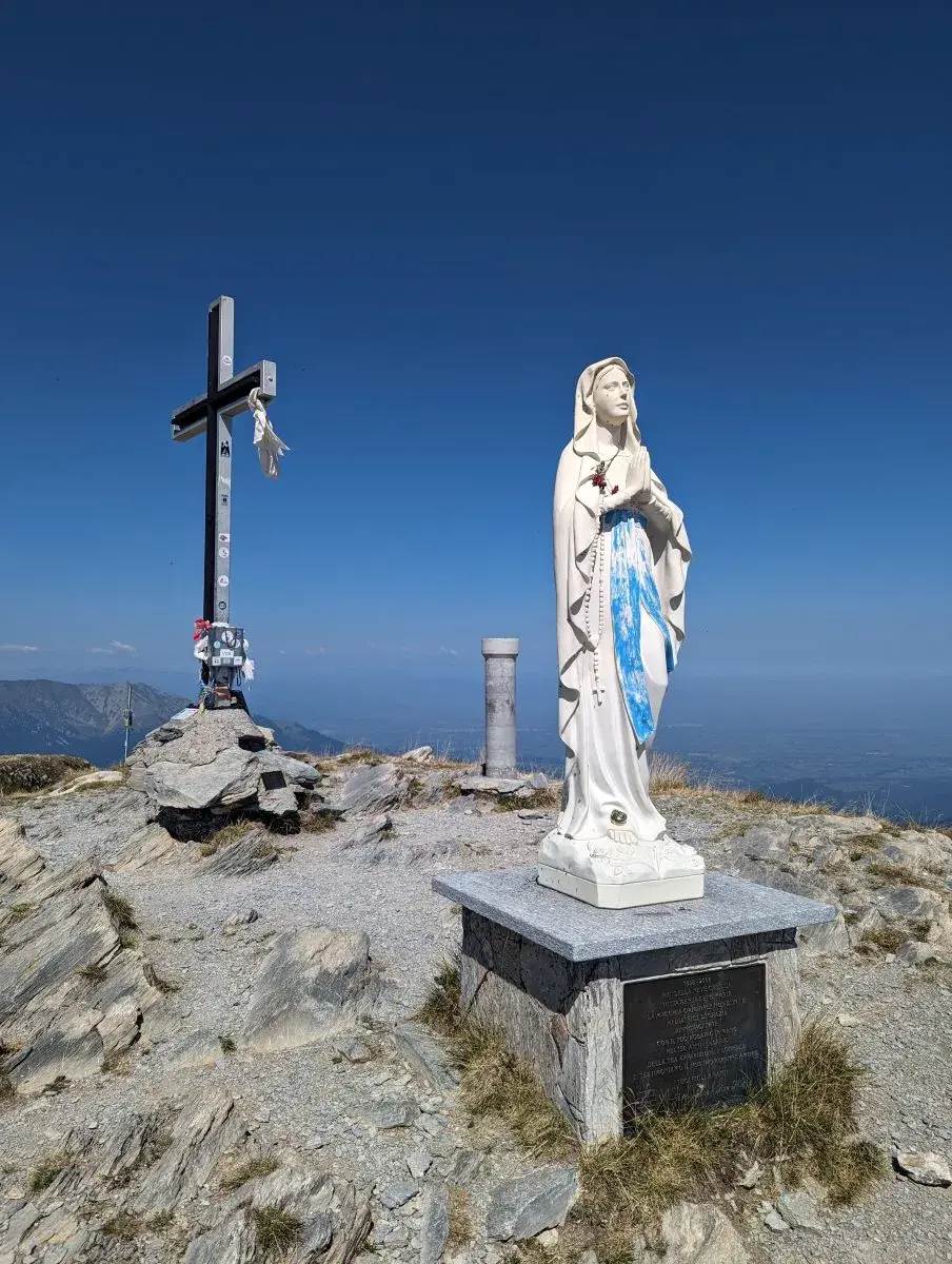 Gipfelkreuz und Madonnenstatue auf dem Gipfel des Monte Mondole