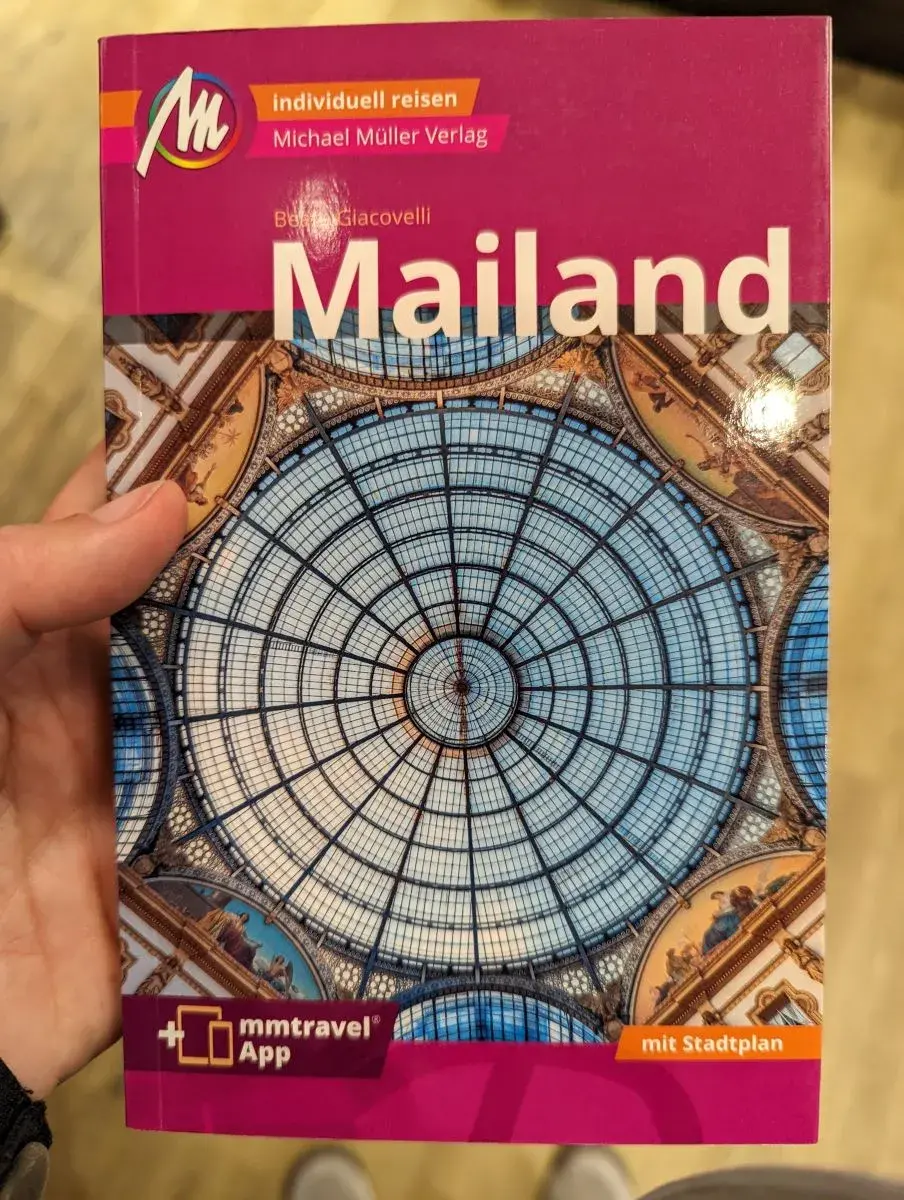 Linda hält den Reiseführer von Mailand in der Hand. Dieser bietet alles Wissenswerte für ein Wochenende in Mailand