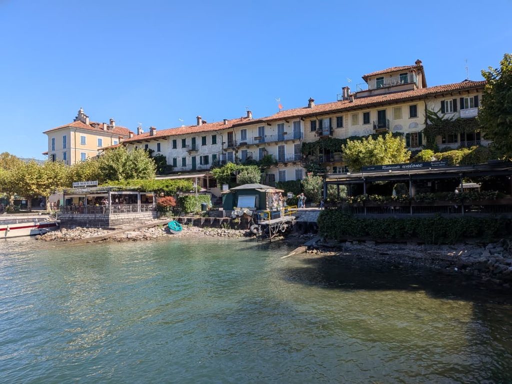 Colorful waterfront houses and restaurants line the shore of Isola dei Pescatori in Lago Maggiore.